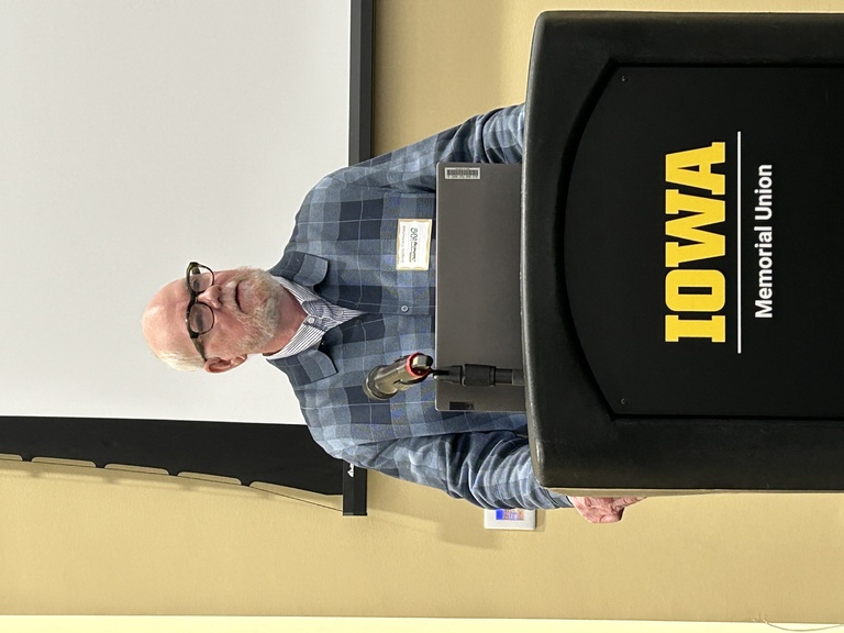 Greg Carmichael at a podium saying University of Iowa
